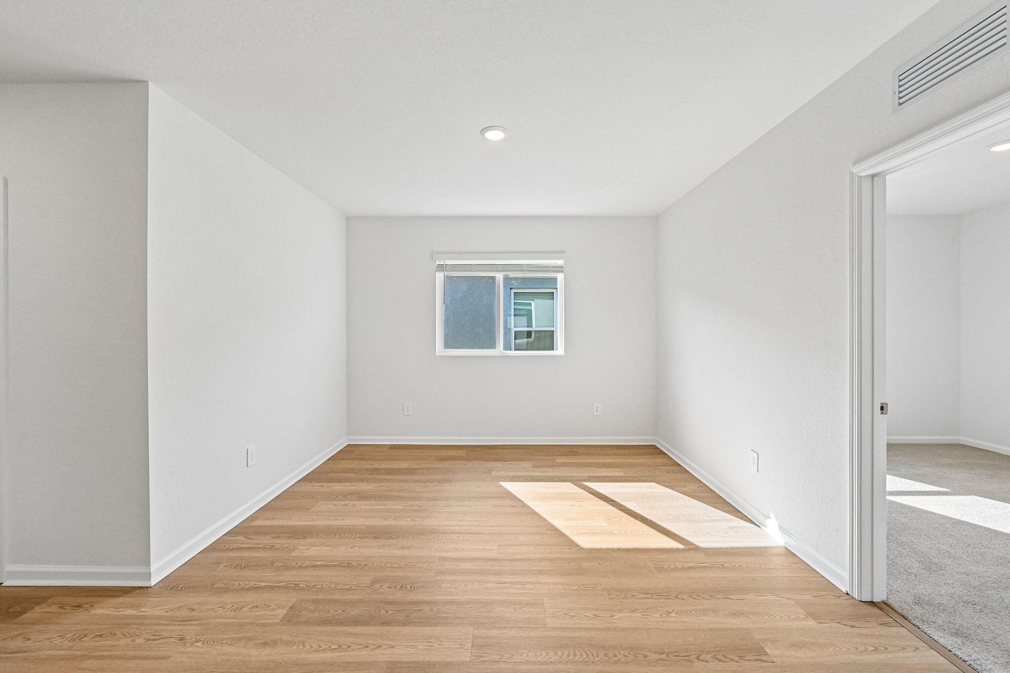 14503 Southwest New Dawn Road Indiantown, FL 34956 - Photo 15 of 42 an empty room with wooden floor and windows