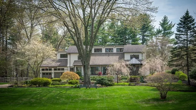 a front view of a house with a garden and trees