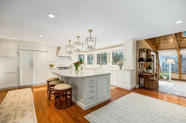 a living room with stainless steel appliances granite countertop furniture wooden floor and a kitchen view