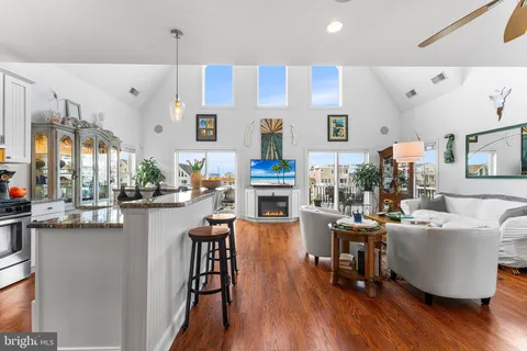 a living room with stainless steel appliances kitchen island granite countertop furniture and a wooden floor