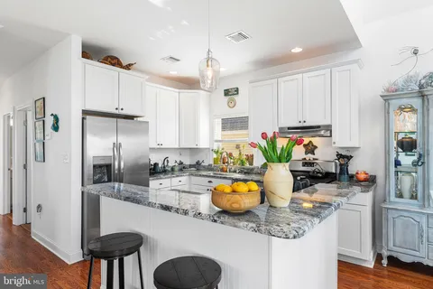 a kitchen with stainless steel appliances granite countertop a sink a stove a refrigerator cabinets and living room view