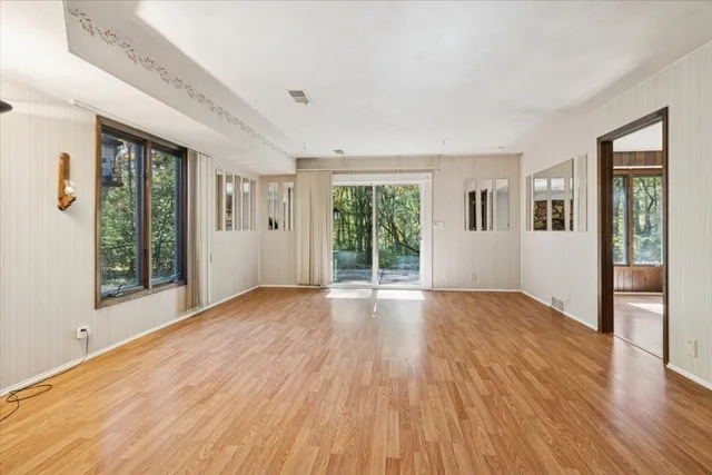 a view of an empty room with wooden floor and a window