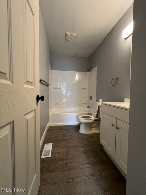 Full bathroom with vanity, toilet, wood-type flooring, and shower / bathing tub combination