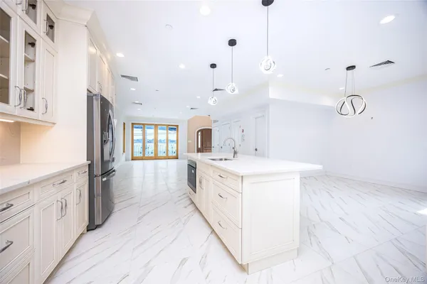 a large kitchen with kitchen island a stove a sink a center island and wooden floor