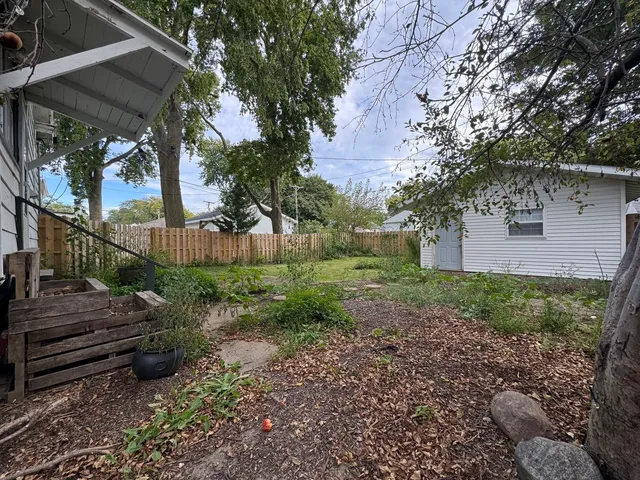 a view of a backyard with wooden fence and a bench