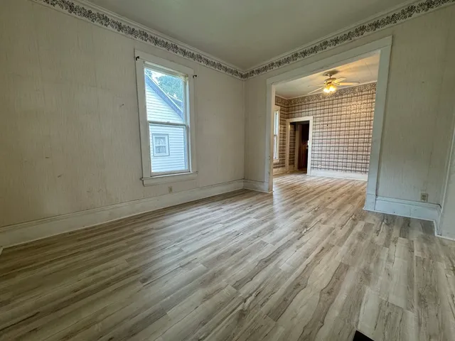 a view of an empty room with wooden floor and a window