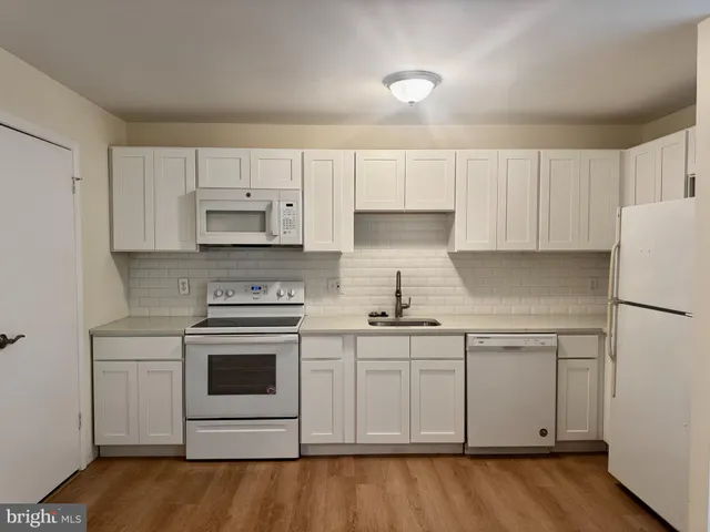 a kitchen with stainless steel appliances granite countertop a stove a sink and white cabinets