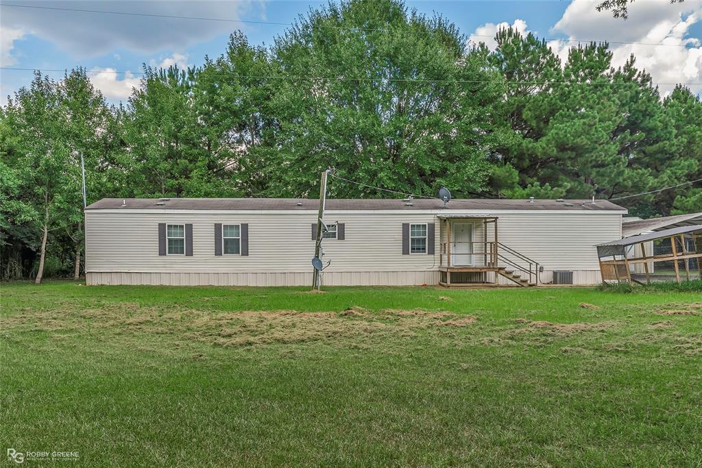 Rear view of house with a yard and view of scattered trees