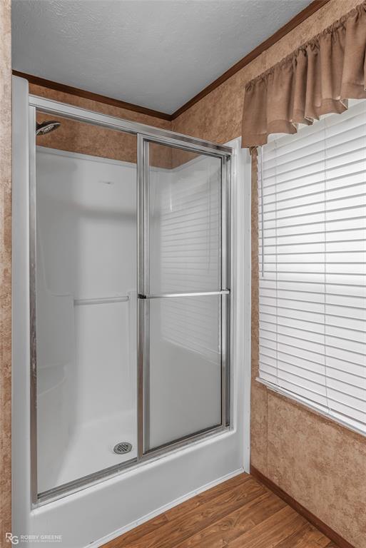 209 Addison Road Mansfield, LA 71052 - Photo 15 of 25 Bathroom with wood finished floors, a shower stall, a textured ceiling, and crown molding