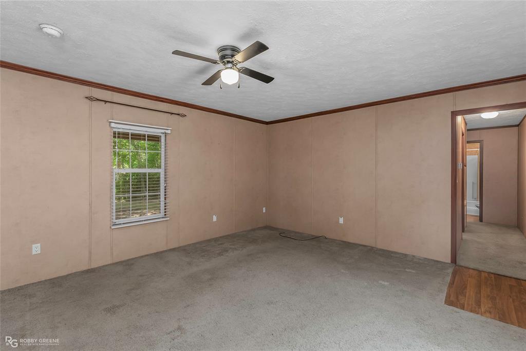 209 Addison Road Mansfield, LA 71052 - Photo 16 of 25 Empty room with crown molding, carpet, a ceiling fan, a textured ceiling, and a decorative wall