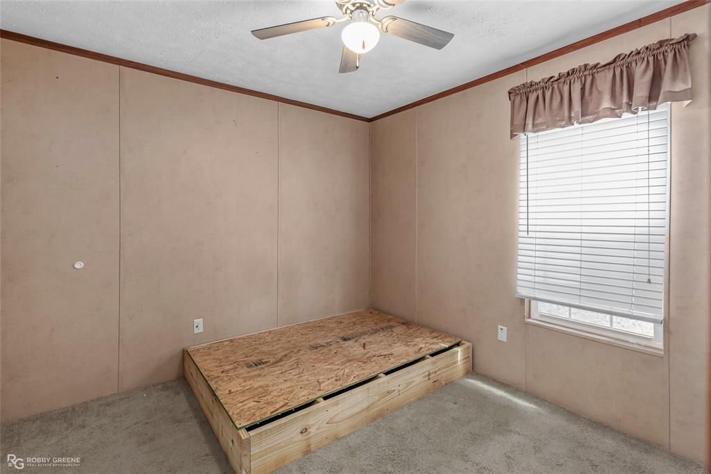 209 Addison Road Mansfield, LA 71052 - Photo 18 of 25 Unfurnished bedroom with ornamental molding, light carpet, a textured ceiling, a decorative wall, and a ceiling fan