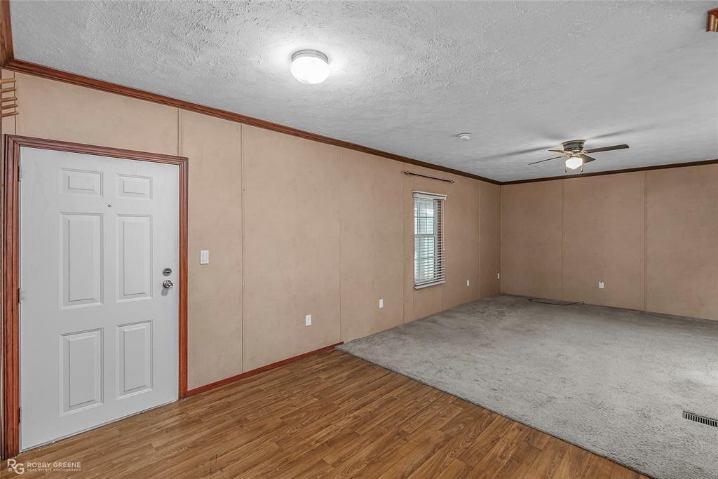 209 Addison Road Mansfield, LA 71052 - Photo 6 of 25 Entrance foyer with crown molding, wood finished floors, a textured ceiling, carpet, and a decorative wall