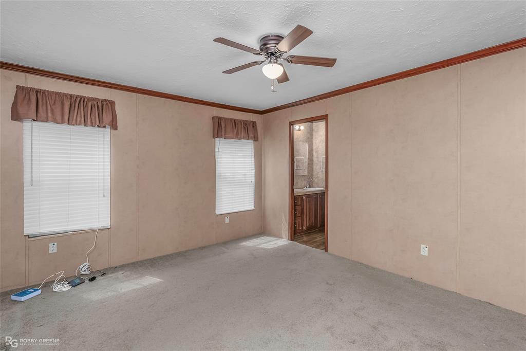 209 Addison Road Mansfield, LA 71052 - Photo 7 of 25 Carpeted spare room with crown molding, a textured ceiling, a ceiling fan, and a decorative wall