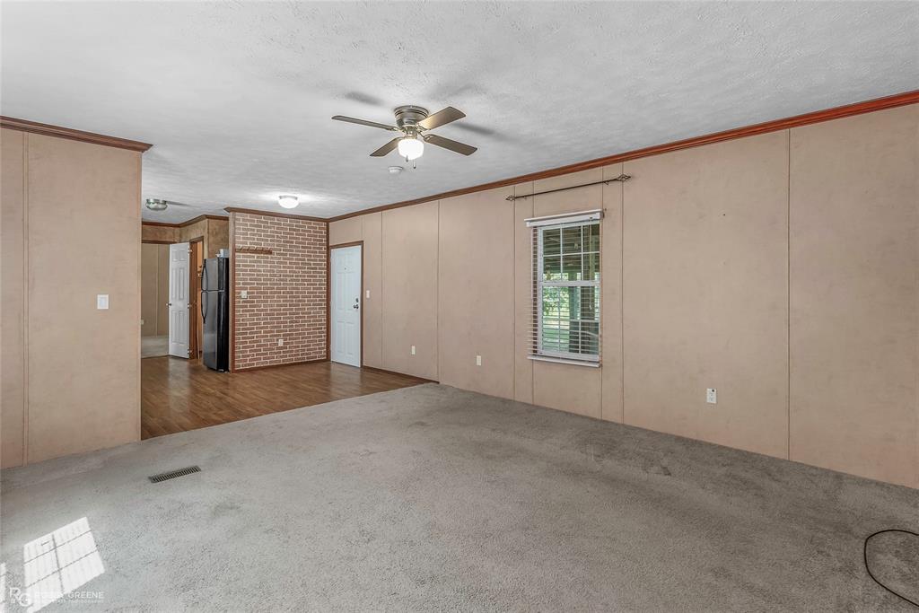 209 Addison Road Mansfield, LA 71052 - Photo 8 of 25 Spare room with crown molding, carpet, a textured ceiling, ceiling fan, and a decorative wall