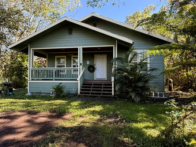 a view of a house with a yard plants and large tree