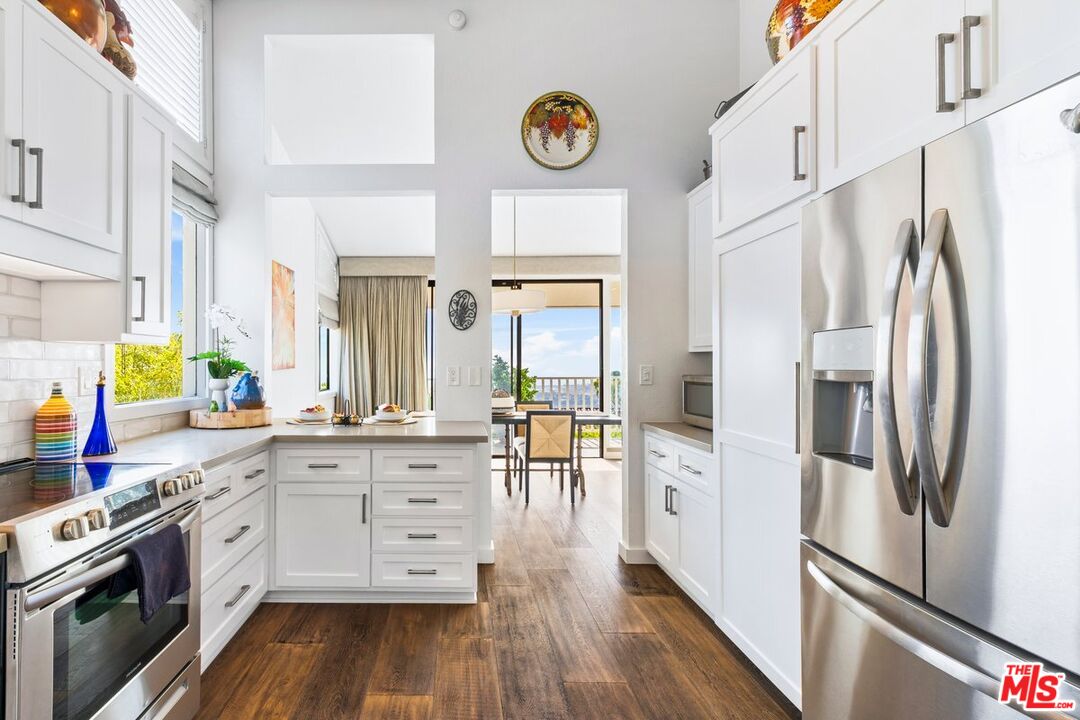 624 Las Alturas Road Santa Barbara, CA 93103 - Photo 6 of 22 a kitchen with stainless steel appliances a refrigerator a stove a sink and white cabinets with wooden floor