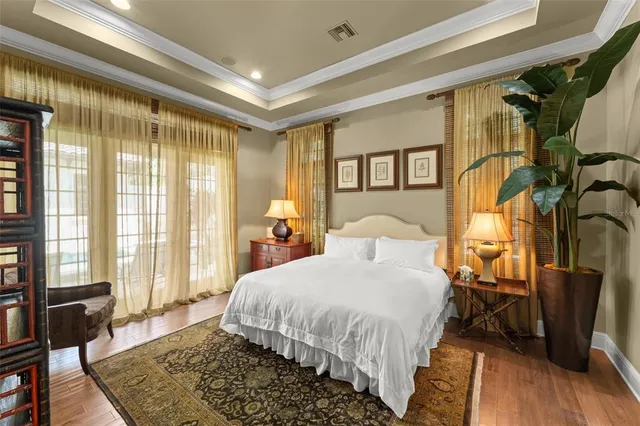 a bedroom with a bed a dresser and wooden floor