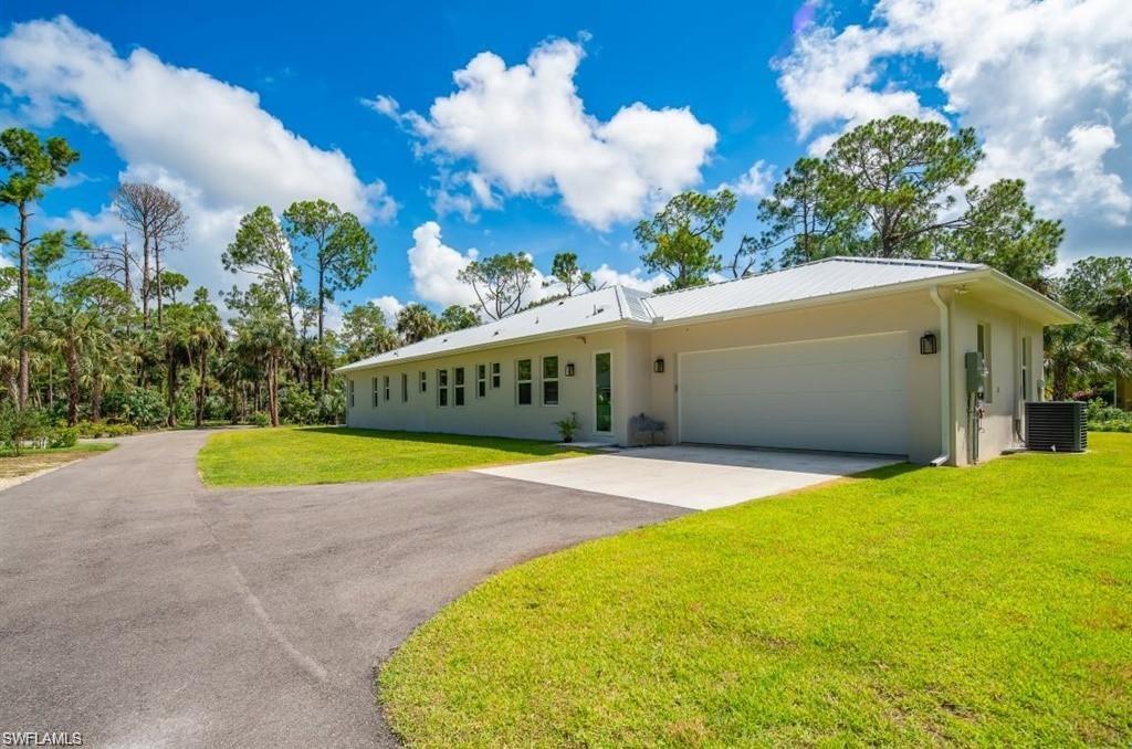 3740 3rd Avenue Southwest Naples, FL 34117 - Photo 14 of 16 Ranch-style home with driveway, a front lawn, stucco siding, an attached garage, and a metal roof