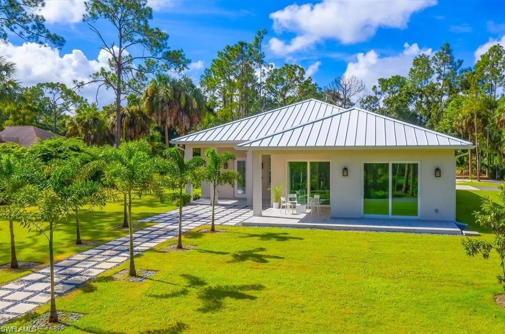 3740 3rd Avenue Southwest Naples, FL 34117 - Photo 16 of 16 Back of house featuring a standing seam roof, a yard, a patio, a metal roof, and stucco siding