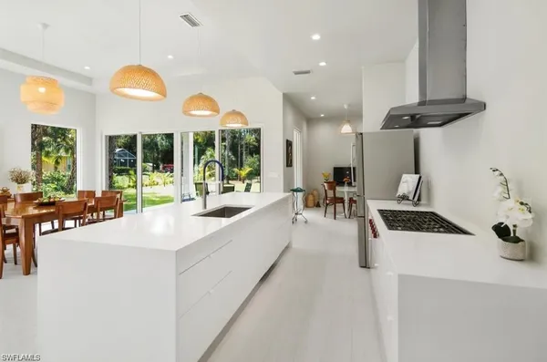 a large white kitchen with a large window and stainless steel appliances