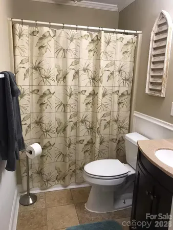 a white toilet sitting next to a shower curtain and a sink