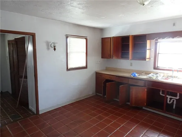 an empty room with kitchen view and a window