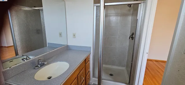 a bathroom with a granite countertop shower sink vanity and mirror