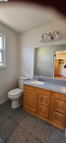 a bathroom with a granite countertop sink and a toilet