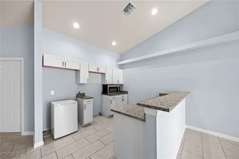 a kitchen with a sink a stove top oven and white cabinets