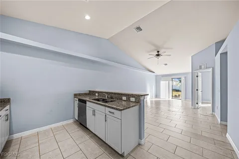 a kitchen with granite countertop a stove a sink and a refrigerator