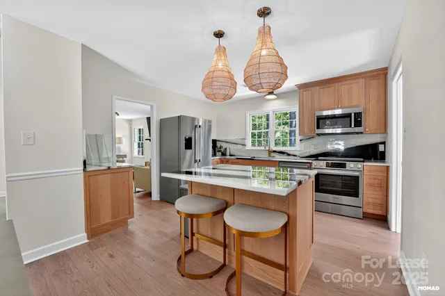 a kitchen with stainless steel appliances granite countertop a stove a sink dishwasher a dining table and chairs with wooden floor