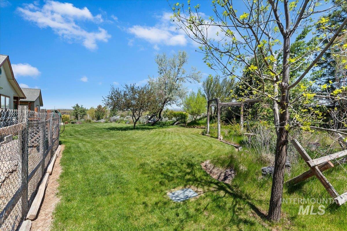 147 East Indian Crk Road Boise, ID 83716 - Photo 36 of 43 Expansive green lawn with mature trees and a chain-link fence bordering the property