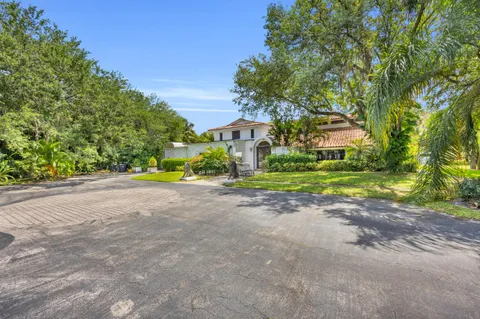 a view of a house with a big yard and large trees