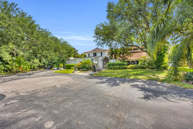 a view of a house with a big yard and large trees