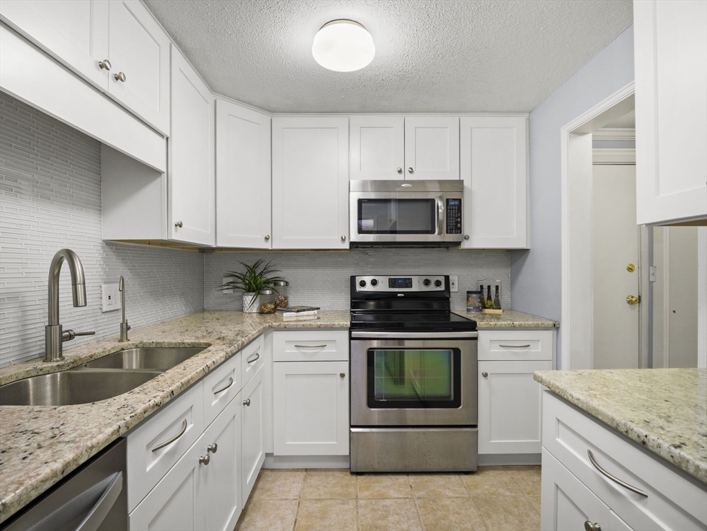 9 Elm Street, Unit 1 Acton, MA 01720 - Photo 13 of 29 a kitchen with stainless steel appliances granite countertop a sink a stove a microwave and cabinets