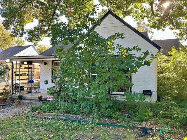 a backyard of a house with table and chairs under an umbrella