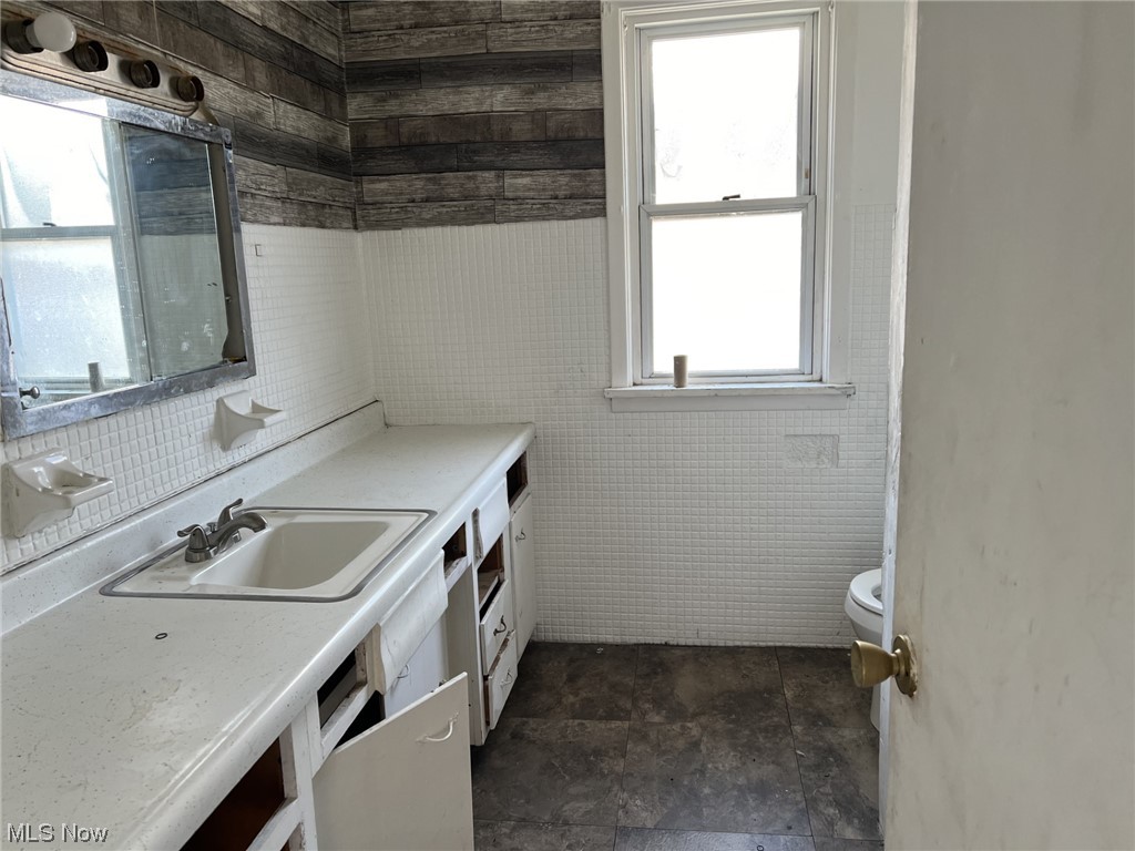 14740 Wemple Road Cleveland, OH 44110 - Photo 11 of 11 Kitchen featuring dark tile flooring, a healthy amount of sunlight, sink, and tile walls