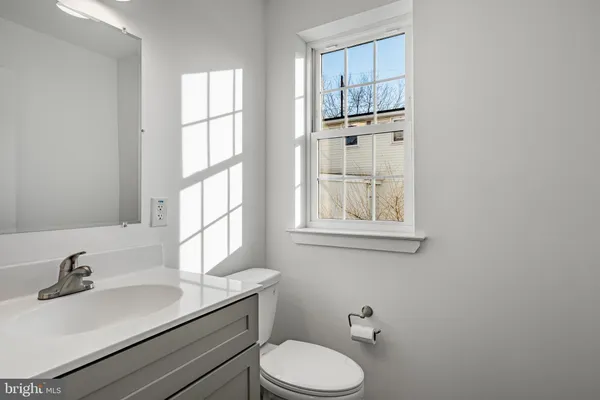 a bathroom with a sink toilet a mirror and window