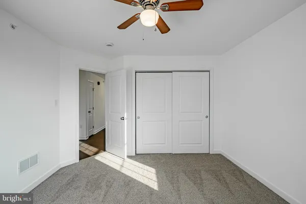 a view of an empty room and chandelier fan