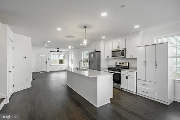 a kitchen with stainless steel appliances granite countertop a refrigerator a stove a sink dishwasher a oven and white cabinets with wooden floor