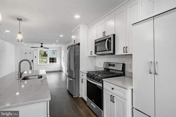 a kitchen with stainless steel appliances granite countertop a sink a stove a refrigerator cabinets and a dining table