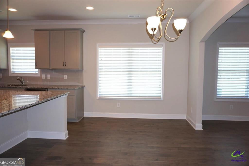 121 Bluecoat Trail Byron, GA 31008 - Photo 25 of 45 a kitchen with stainless steel appliances granite countertop a sink a window and wooden floors