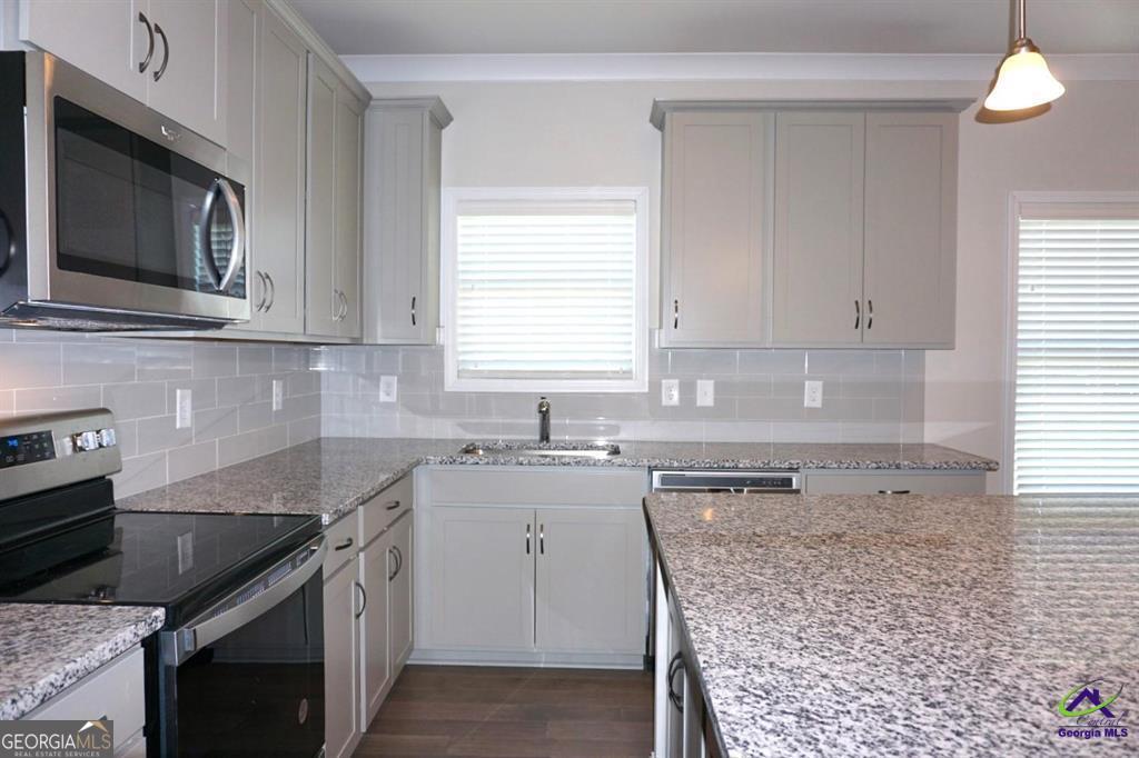 121 Bluecoat Trail Byron, GA 31008 - Photo 27 of 45 a kitchen with granite countertop a sink stove and microwave