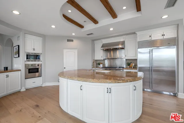 a large kitchen with stainless steel appliances a large counter top a sink and a refrigerator