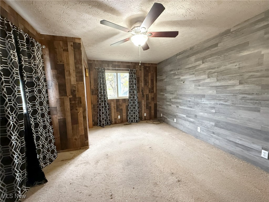 4589 Harmon Creek Road Colliers, WV 26035 - Photo 22 of 26 Spare room featuring carpet, wooden walls, a textured ceiling, and a ceiling fan