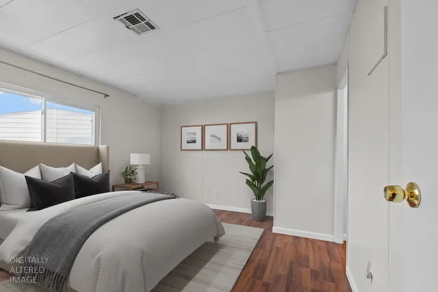 a bedroom with a large bed and wooden floor