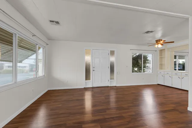 a view of an empty room with wooden floor and a window