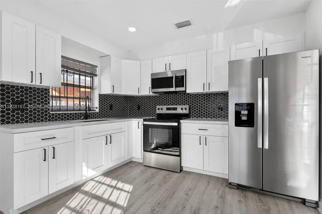 a kitchen with stainless steel appliances white cabinets and a refrigerator