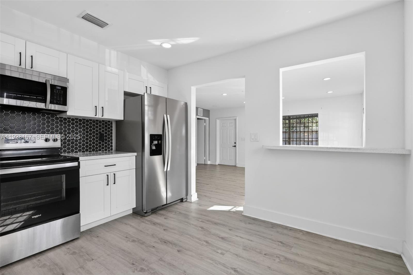 708 Southwest 10th Street, Unit 1 Dania Beach, FL 33004 - Photo 3 of 23 a open kitchen with stainless steel appliances granite countertop a stove a refrigerator and a microwave