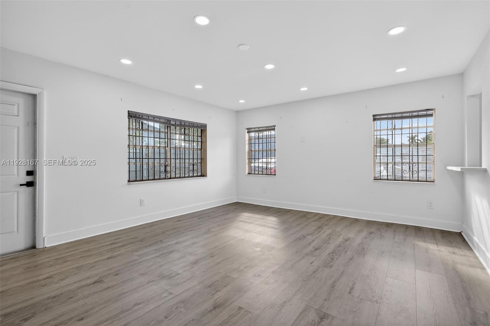 708 Southwest 10th Street, Unit 1 Dania Beach, FL 33004 - Photo 6 of 23 a view of an empty room with wooden floor and windows